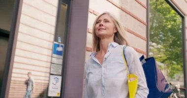 Gri saçlı gülümseyen Olgun kadın omzunu yavaş üzerinden şehir alışveriş torbaları sokakta yürüme