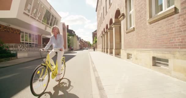 Smilende Moden Kvinne Med Grått Hår Som Sykler Gjennom Byen stockvideo