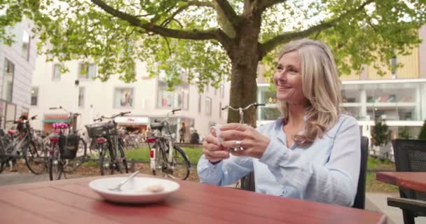 Sonriente Mujer Madura Sosteniendo Una Taza Café Fresco Mientras Sienta — Vídeos de Stock