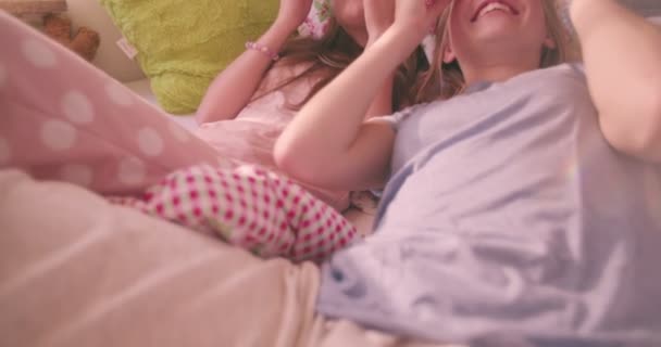 パジャマ パーティーをしながら 彼らの目にキュウリを置くことによって自分自身の美容トリートメントを与えて自分のパジャマでベッドに横たわっている 人の十代女の子 — ストック動画