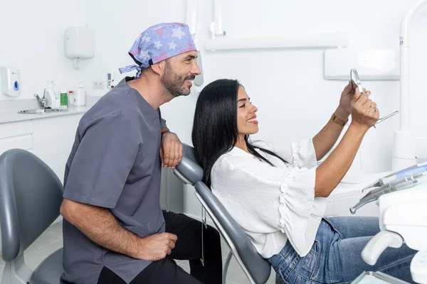 Kobieta Klient Patrząc Zęby Lustrze Obok Dentysty Pokoju Kliniki Dentystycznej — Zdjęcie stockowe