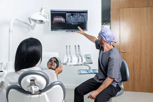 Mężczyzna Dentysta Pokazując Rentgen Kobiecie Patinet Który Siedzi Krześle Pokoju — Zdjęcie stockowe