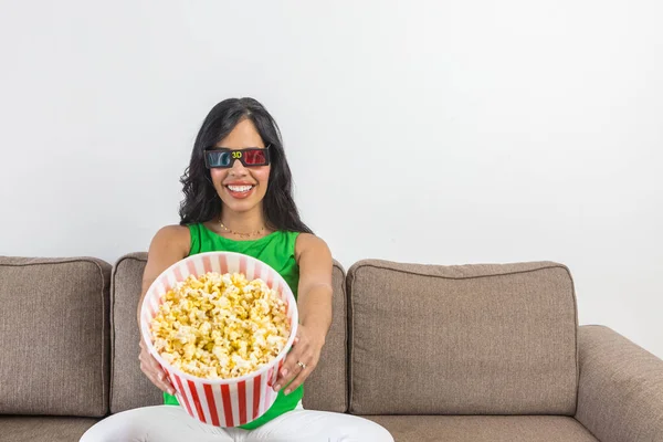 Hispanic Woman Glasses Smiling Demonstrating Bucket Popcorn Camera While Sitting — стокове фото