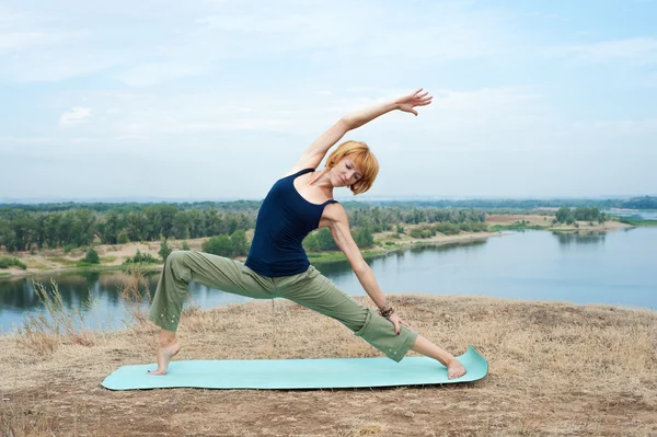 Mädchen praktiziert Yoga auf dem Fluss Stockfoto