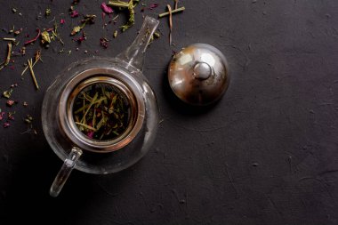 Siyah arka planda çay demliği manzarası, rahatlatıcı çay hazırlama konsepti.