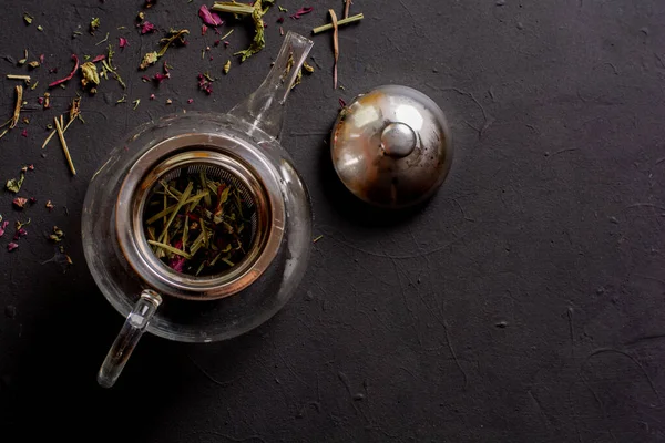 Siyah arka planda çay demliği manzarası, rahatlatıcı çay hazırlama konsepti.
