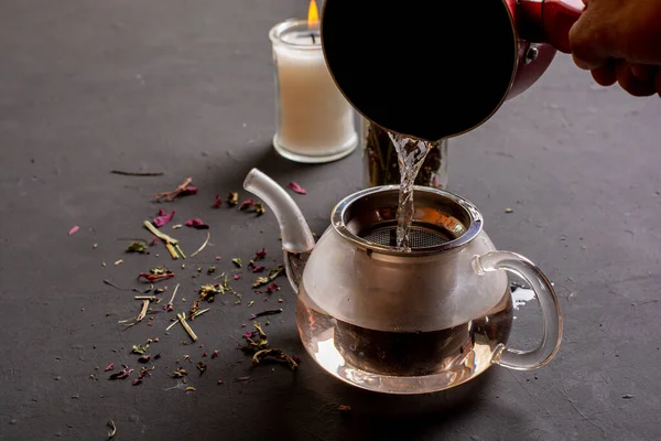 Çay eşliğinde çaydanlığın yan görünüşü, siyah zemine sıcak su eklenmesi, rahatlamanıza yardımcı olması için çay hazırlama kavramı