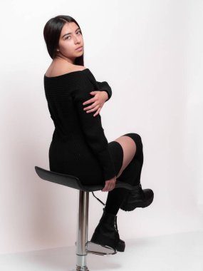 Beyaz arka planda izole edilmiş dönen sandalyede oturan güzel Latin kız. Stüdyo fotoğraf çekimi konsepti.