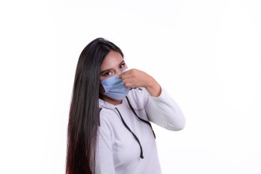 İspanyol kız elinde cerrahi maske, enfeksiyona karşı kişisel bakım konsepti tutuyor.