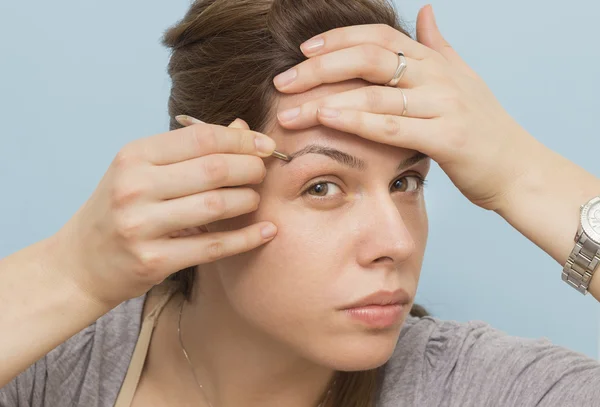 Uma jovem mulher moldando suas sobrancelhas — Fotografia de Stock