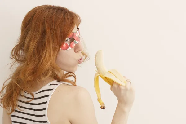 Superhero girl wearing mask with strawberries holding a banana gun — Stock Photo, Image