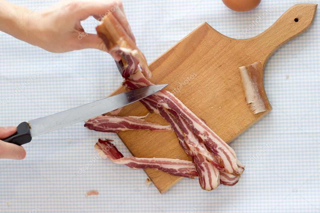 Chef cutting bacon into strips, close up
