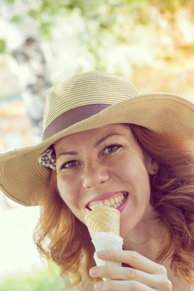 Beautiful smiling girl in a summer hat eating ice cream cone — Stock Photo, Image