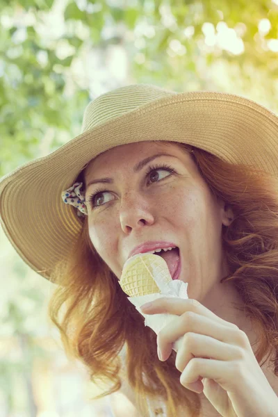 Hermosa chica sonriente en un sombrero de verano comiendo helado cono — Foto de Stock