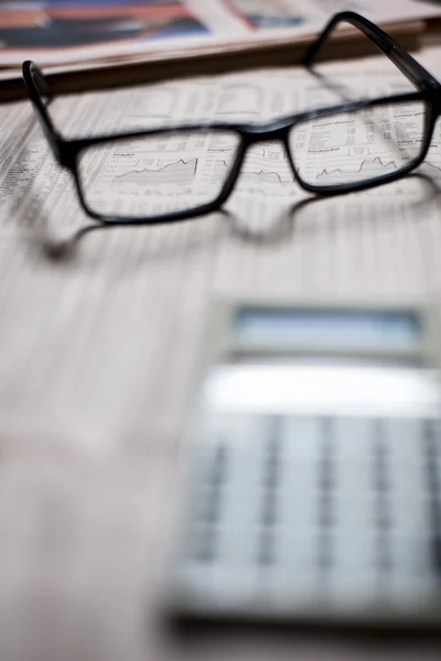 Defokussierter Taschenrechner und fokussierte Brille auf eine Zeitung. — Stockfoto