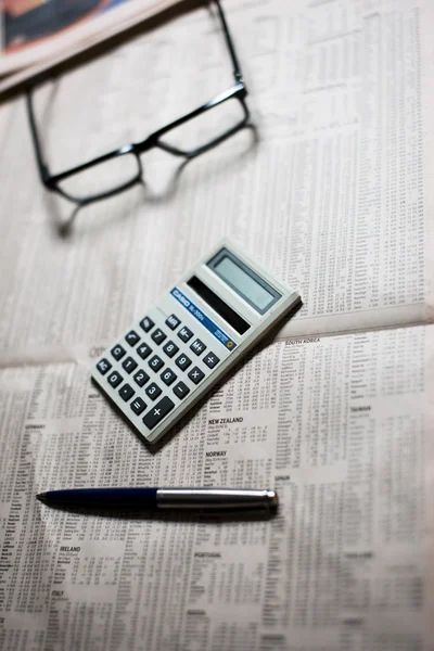 Stock market data, glasses and calculater on a newspaper. — Stock Photo, Image