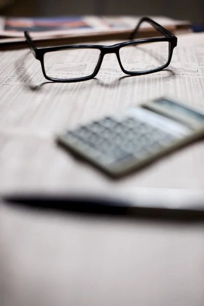 Miniräknare och en glasögon på en tidning. — Stockfoto