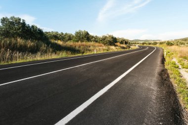 Gün ışığında kırsal yol geçmişini bükmek.