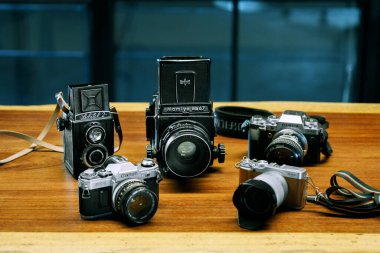İzmir, Türkiye - 9 Temmuz 2021: Ahşap zemin üzerinde Lubitell 2, Mamiya RB67, Fujifilm xt4, Canon AE1 ve Fujifilm xA2 Camera 'nın illüstrasyon çekimi.