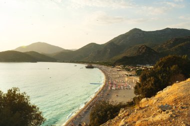 Mugla, Türkiye - 6 Eylül 2021: Fethiye Mugla Türkiye 'deki Belcekiz plajının üst manzarası. Gökyüzünde paraşütle atlayan insanlar