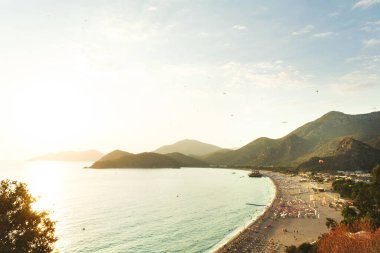 Mugla, Türkiye - 6 Eylül 2021: Fethiye Mugla Türkiye 'deki Belcekiz plajının üst manzarası. Gökyüzünde paraşütle atlayan insanlar