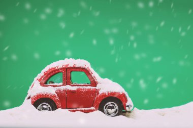 Mat yeşil arka planda oyuncak model bir arabanın yakın plan görüntüsü ve karla kaplı..