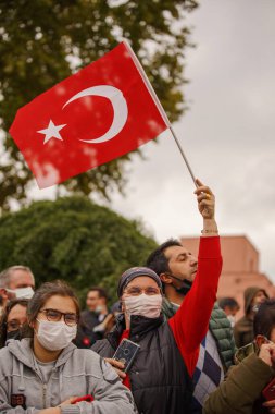 İstanbul, Türkiye - 29 Ekim 2021: Cumhuriyet Günü 'nü kutlamak için elinde Türk bayrakları tutan maskeli bir kadın. Fatih İstanbul Vatan Bulvarı 'nda editör çekimi.