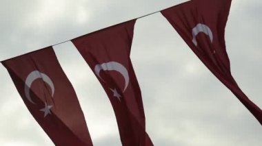 Türk bayraklarından üçü bulutlu bir arkaplanda dalgalanıyor