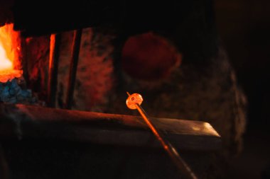 Close up shot of pruducing evil eye or amulet near the furnace. The amulet is red because its scorching.