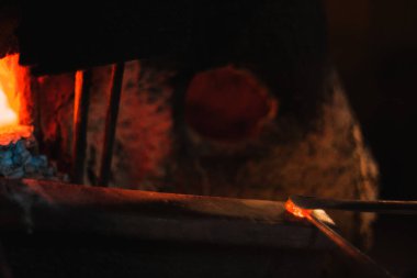 Close up shot of pruducing evil eye or amulet near the furnace. The amulet is red because its scorching.