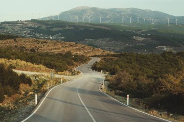 Tepelerde yel değirmenleri olan köy yolunu bükmek.. 