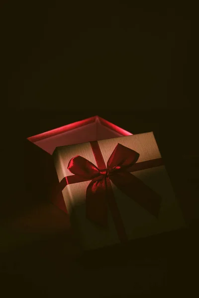 Pudełko Czerwoną Wstążką Ciemnym Tle Miejscowym Światłem — Zdjęcie stockowe