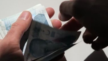 Beyaz arka planda 100 Türk lirası banknot sayılıyor.