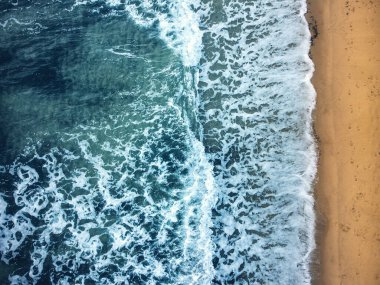 Mavi renkli denizi ve sarı kumsalı olan bir sahilin havadan görünüşü..