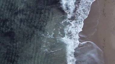 Kum plajının köpüklü dalgalı havadan görüntüsü