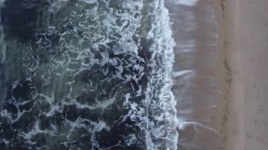 Kum plajının köpüklü dalgalı havadan görüntüsü