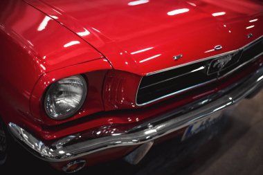 İzmir, Türkiye - 4 Aralık 2021: Fuar İzmir 'de bir otomobil fuarında kırmızı renkli klasik bir Ford Mustang arabasının ön görüntüsü.