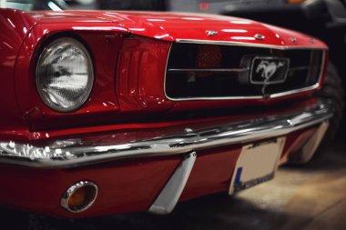 İzmir, Türkiye - 4 Aralık 2021: Fuar İzmir 'de bir otomobil fuarında kırmızı renkli klasik bir Ford Mustang arabasının ön görüntüsü.