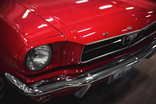 İzmir, Türkiye - 4 Aralık 2021: Fuar İzmir 'de bir otomobil fuarında kırmızı renkli klasik bir Ford Mustang arabasının ön görüntüsü.