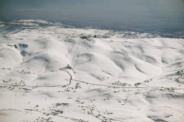 Bir uçak penceresinden karlı dağların havadan görünüşü