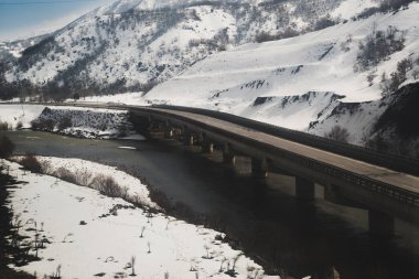 Kışın karlı bir çevreyle bir köprü manzarası.