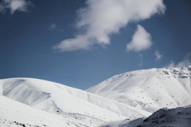 Karlı ve bulutlu dağların manzarası.