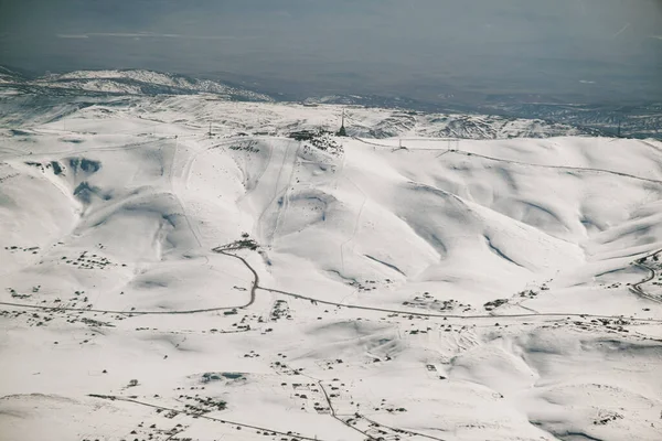 Bir uçak penceresinden karlı dağların havadan görünüşü