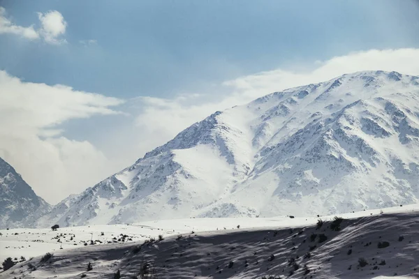 Karlı ve bulutlu bir dağın manzarası.