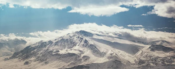 Karlı ve bulutlu dağların manzarası.