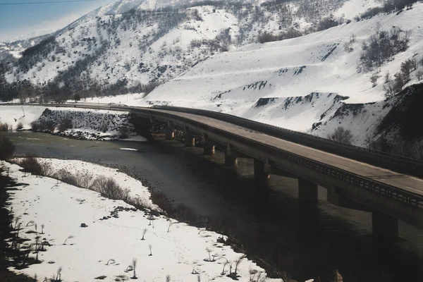 Kışın karlı bir çevreyle bir köprü manzarası.