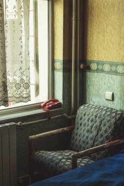 Kırmızı telefonu olan eski moda bir otel odasında eski moda bir koltuk..