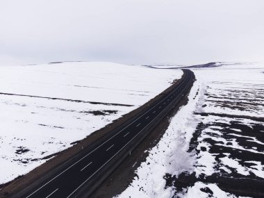 Kışın tek şeritli ve karlı bir yolun hava çapraz görüntüsü..