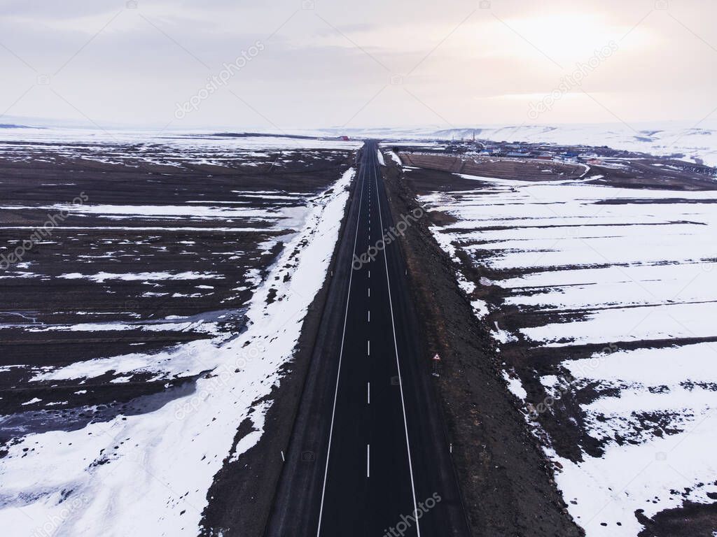 Aerial view of a road with one lane and snow in winter.