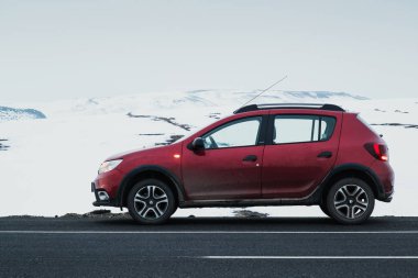Kars, Türkiye - 25 Şubat 2022: Kırmızı renkli bir Dacia markası olan Sandero 'nun yan görüntüsü, karlı bir arka planı olan asfalt bir yolda durduruldu.